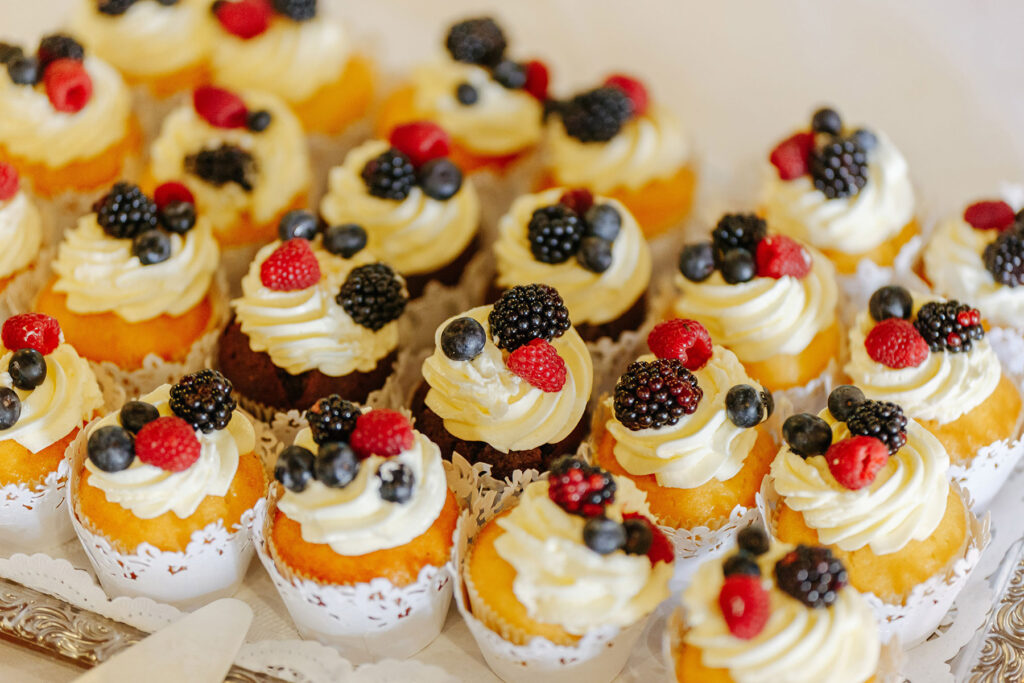 Kleine Törtchen mit Sahnehaube und Beeren bilden eine appetitliche Auswahl für Hochzeiten auf dem Landhof Liepe.