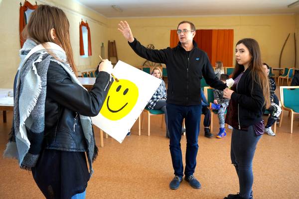 Bei einer deutsch-polnischen Begegnung erklären drei Teilnehmende eine Übung mit einem Plakat und einem gelben Smiley.